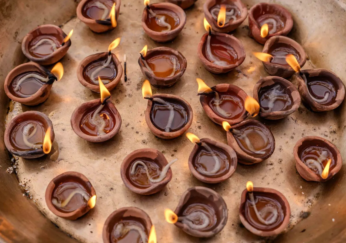 Rows of small lit clay diyas arranged on a tray for Diwali
