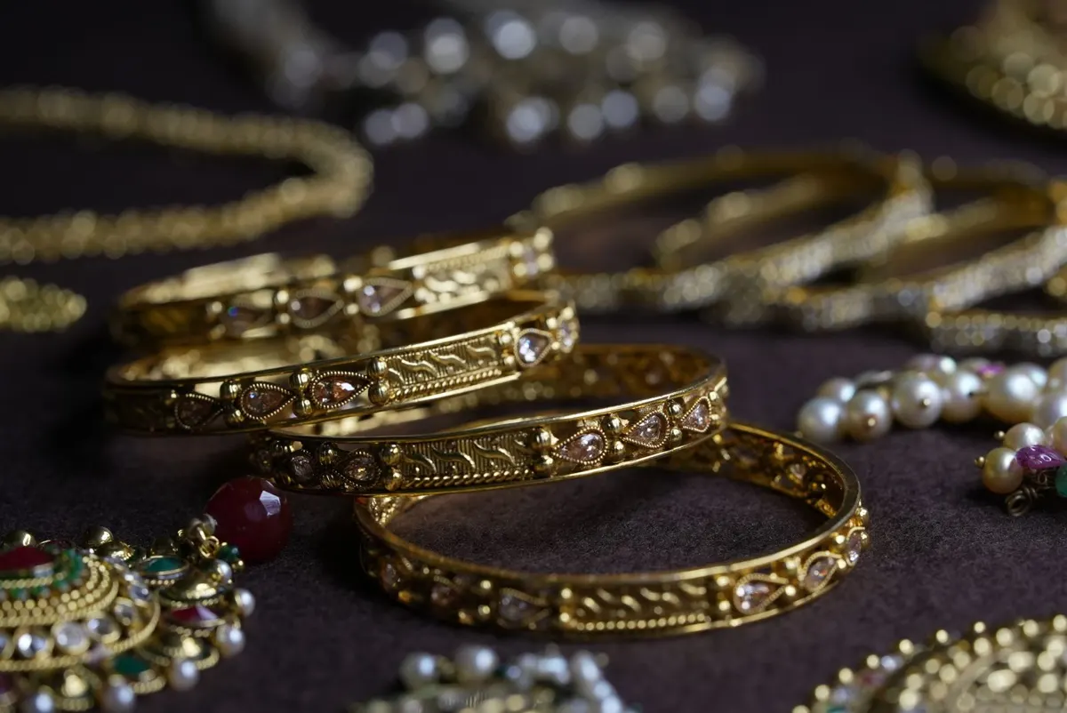 Close-up of intricate gold bangles and jewellery pieces on a dark cloth