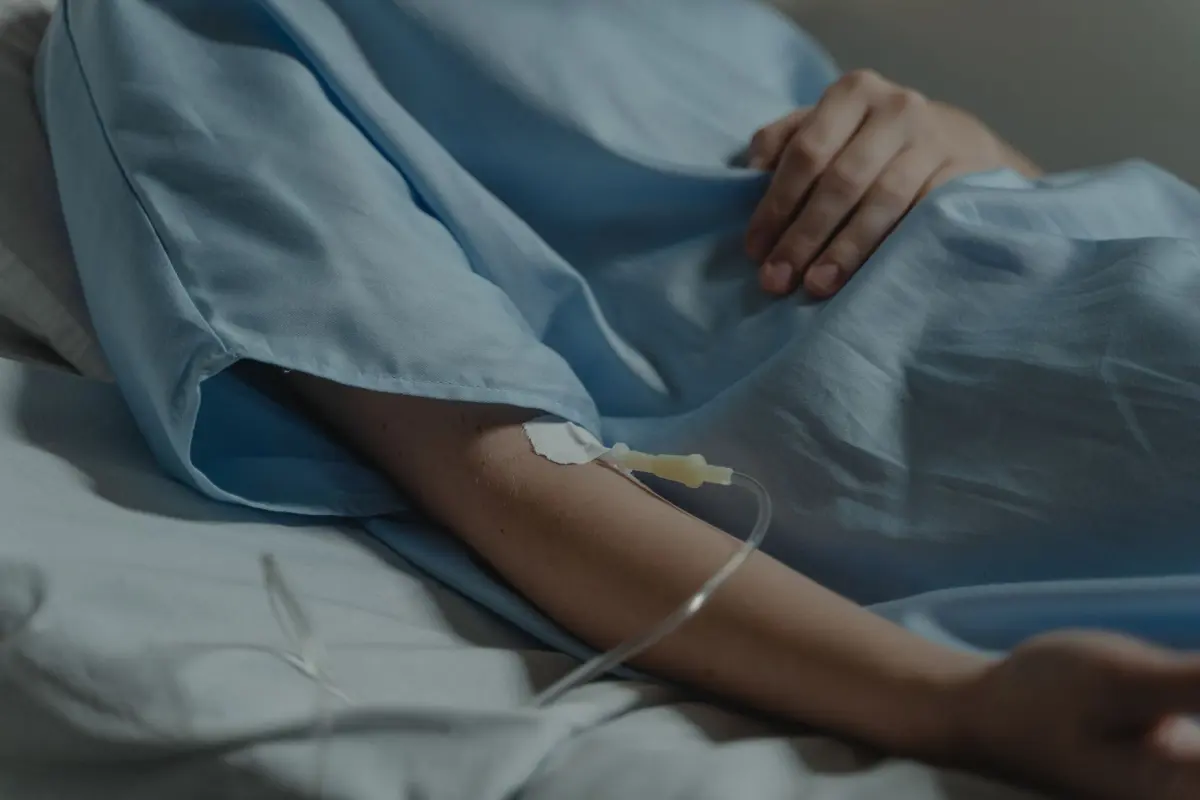 Patient's arm on a hospital bed with an IV drip, as families plan cancer treatment cost in India