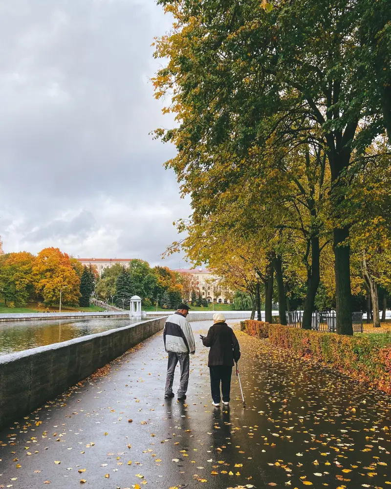 Elderly couple walking along an autumn park path, representing pensioners getting dearness relief