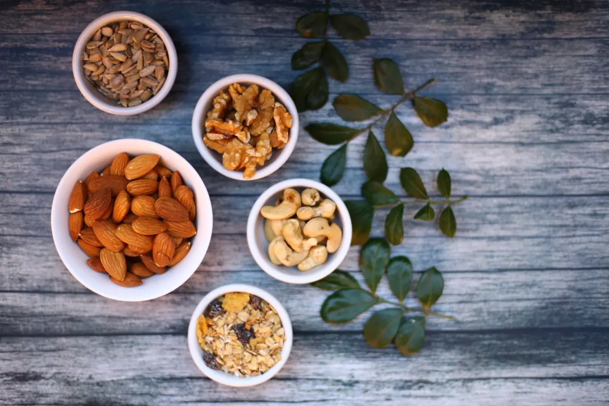 Small white bowls of almonds, cashews, walnuts and seeds on a wooden table, a typical part of a Karwa Chauth sargi
