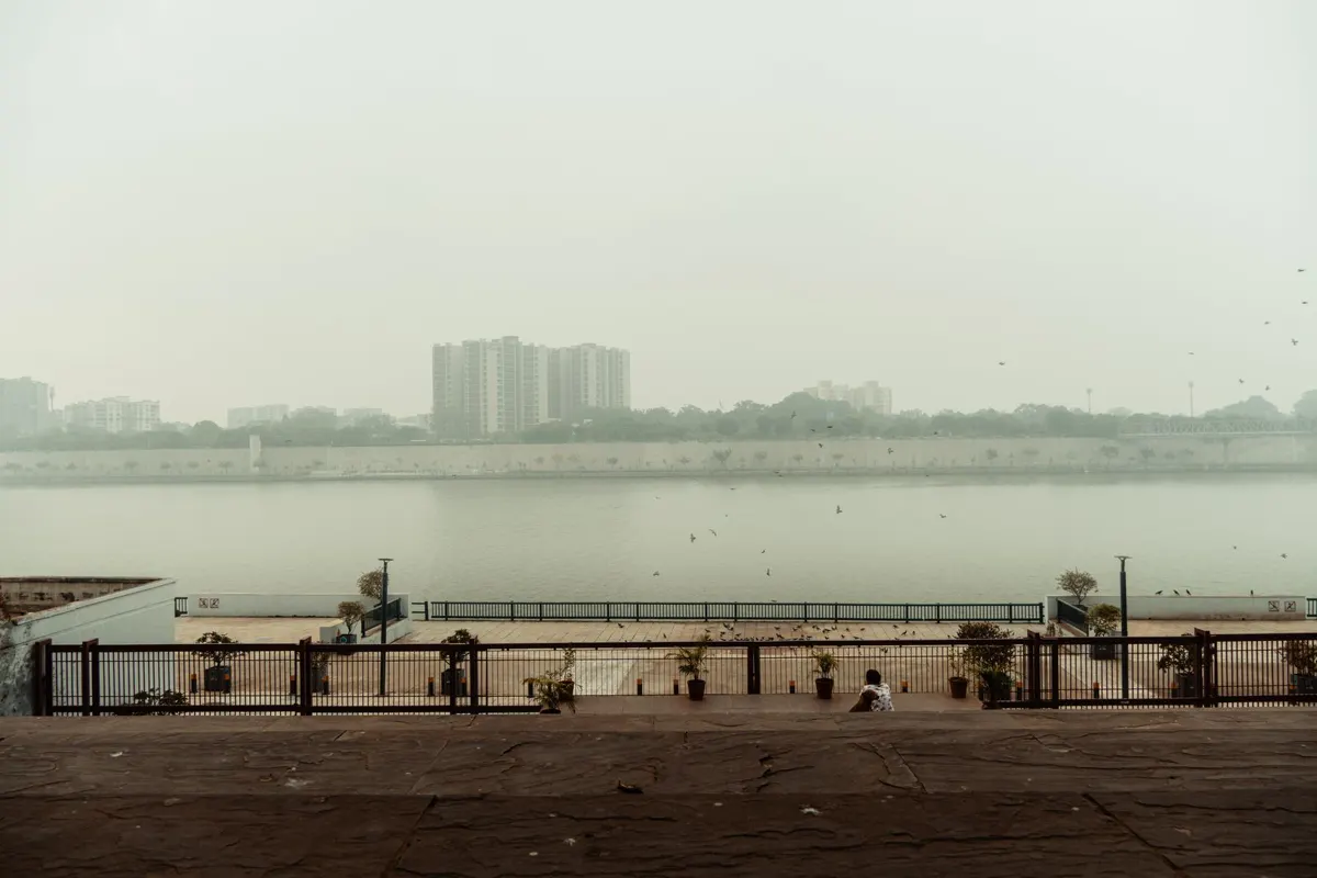 Thick grey smog hanging over a riverfront and apartment towers in an Indian city